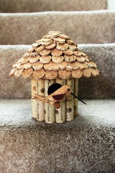 a birdhouse made out of wine corks sitting on the steps in front of some stairs