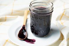 a jar of blueberry jam on a plate with a spoon