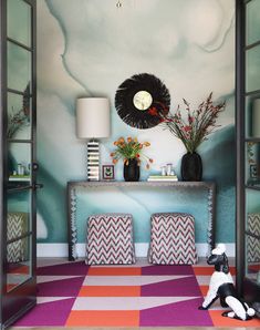 a living room with colorful carpeting and walls painted in different shades of blue, pink, orange and white