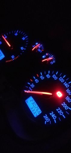 the speedometers are glowing in the dark with blue and red lights on them