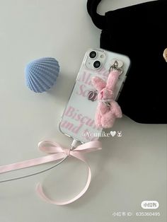 an iphone case with a pink bow on it next to a seashell and other items