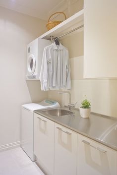 a laundry room with white cabinets and stainless steel sink