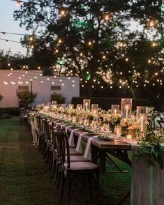 a long table with candles, flowers and greenery is set up for an outdoor dinner