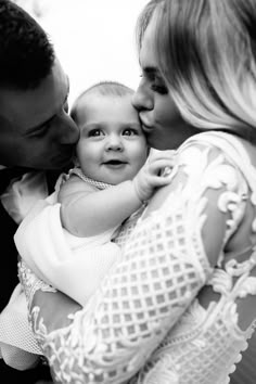 a man and woman are holding a baby in their arms as they kiss each other