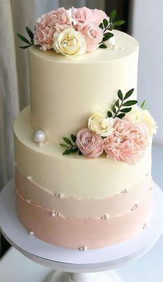 a three tiered cake with pink and white flowers on the top is sitting on a plate