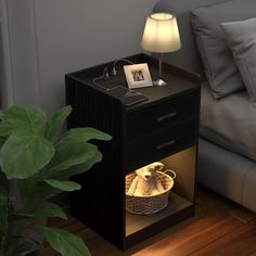 a night stand with a basket on it next to a bed and a plant in the corner