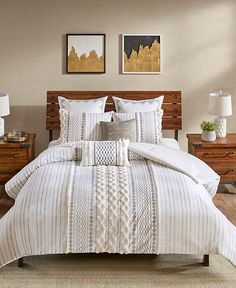 a bed with white comforter and two pictures on the wall above it in a bedroom