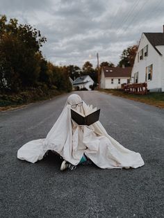 a person sitting on the ground with a book in front of their face and covering them