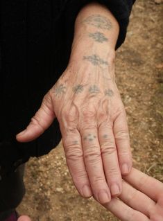 two people holding hands with small tattoos on their palms and fingers, one person has his hand in the other's palm