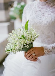 a woman in a wedding dress holding a bouquet of flowers and wearing a ring on her finger