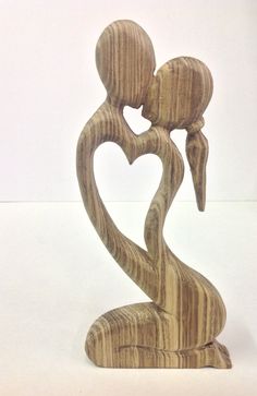 a wooden sculpture holding a baby in the shape of a heart on a white background