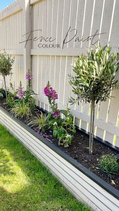 some plants are growing in the corner of a fenced off area with grass and flowers