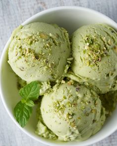 three scoops of green tea ice cream in a white bowl with mint sprinkled on top