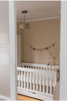 a baby's crib in the corner of a room with lights hanging from the ceiling