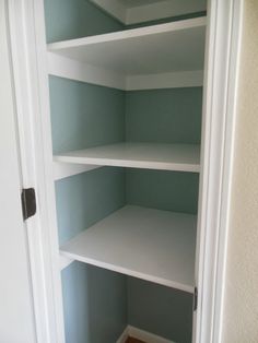 an empty closet with white shelves in it