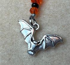 an orange beaded necklace with a silver dragon charm on it's end is laying on the floor