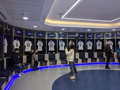 a group of people standing in front of lockers with shirts hanging on the wall