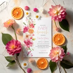 an orange and pink flower baby shower is surrounded by flowers, leaves, and fruit