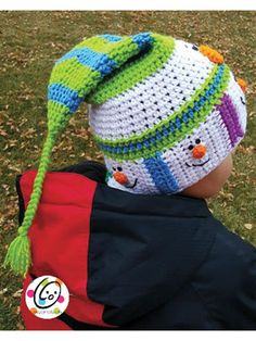 a small child wearing a crocheted hat while sitting in the grass with his back to the camera