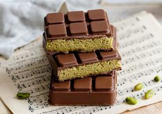 three pieces of chocolate and pistachio on top of sheet music paper with notes