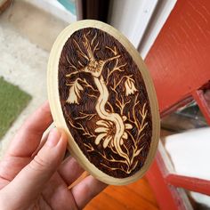 a hand holding a wooden box with an image of a dragon on the inside of it