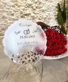 two heart shaped flowers are in front of a wedding cake with the date written on it