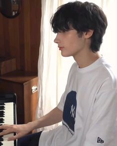 a young man sitting in front of a piano