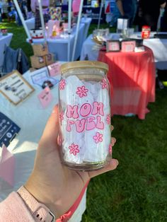 a person holding up a jar with the word mom on it and flowers painted on it