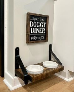 two white bowls are sitting on a wooden shelf in front of a sign that says doggy diner