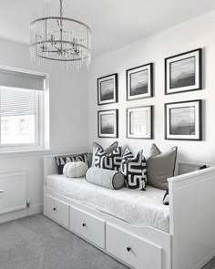 a white daybed with lots of pillows and pictures on the wall