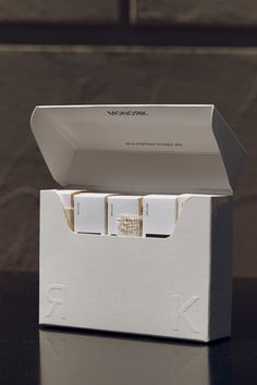 an open white box with three pieces of paper in it sitting on a black table