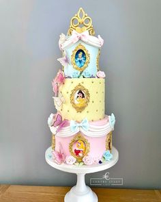 a three tiered cake with princess figurines on the top and bottom layer