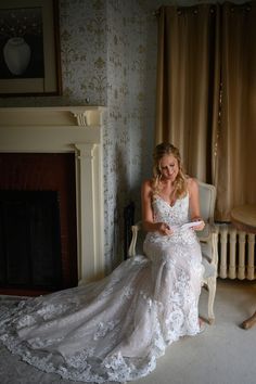 a woman sitting on a chair in front of a fire place wearing a wedding dress