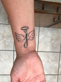 a person's arm with a tattoo on it that has an angel wing in the middle