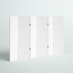 four white partitions are standing in the middle of a plain room with no walls