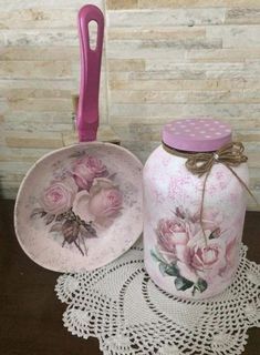 two jars with pink flowers on them are sitting on a doily next to a crocheted doily