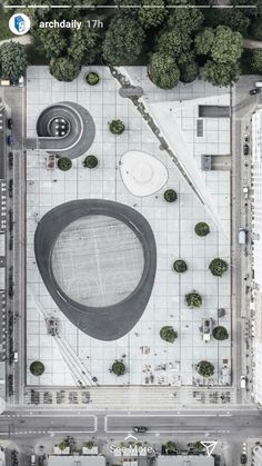 an aerial view of a parking lot in front of a building with trees around it