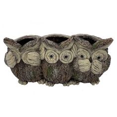 four owls sitting on top of each other in a tree trunk planter with their eyes wide open