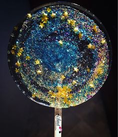 a blue and gold glitter covered lollipop with stars on it