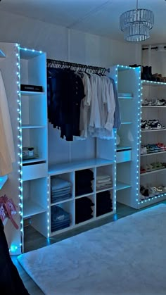 the closet is lit up with blue lights and white shelving units, which are filled with clothes