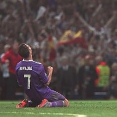 a soccer player sitting on the ground in front of a crowd with his hands up