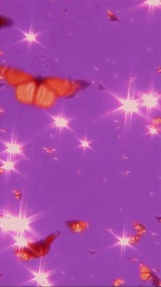 a group of orange butterflies flying through the air with stars in the sky behind them