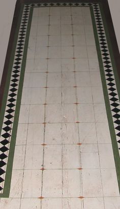 a white and green tiled floor with a black and white border on it's edge