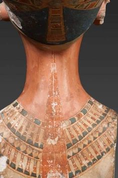 an ancient vase with egyptian designs on it's face and neck, in the shape of a headdress