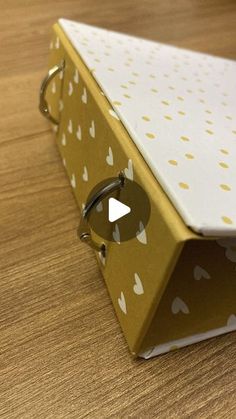 an origami box with hearts on it sitting on top of a wooden table