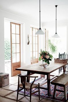 a dining room table with two benches and flowers in a vase on the table next to it