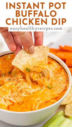 a hand dipping a tortilla chip into a bowl of chicken dip