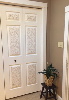 a potted plant sitting on top of a wooden stool in front of a white door