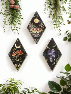 three wall hangings with flowers and plants on the wall next to eachother