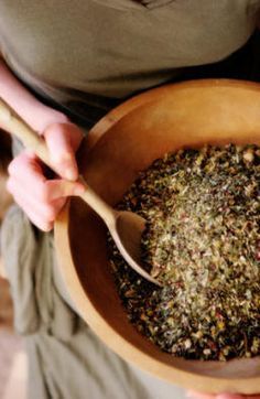 a person holding a wooden bowl filled with food and a spoon in their hand,